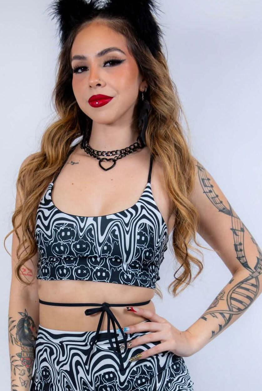 Front-facing view of the Meltdown Lush Top, featuring the bold melty smiley pattern and confident pose.