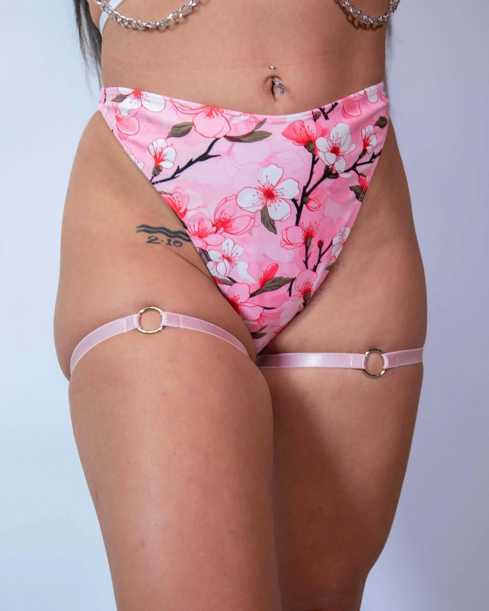 Light pink leg garters with o-ring detail paired with floral high-waisted bottoms, perfect for rave outfits.