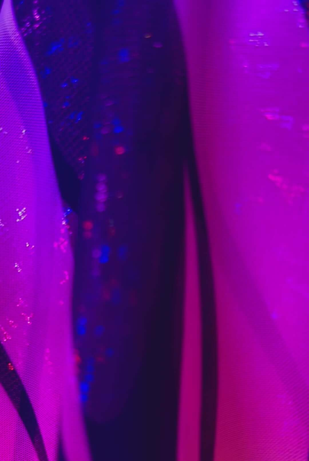 Close-up of vibrant purple and black fabric showcasing a UV reactive design, perfect for rave outfits and clothing.