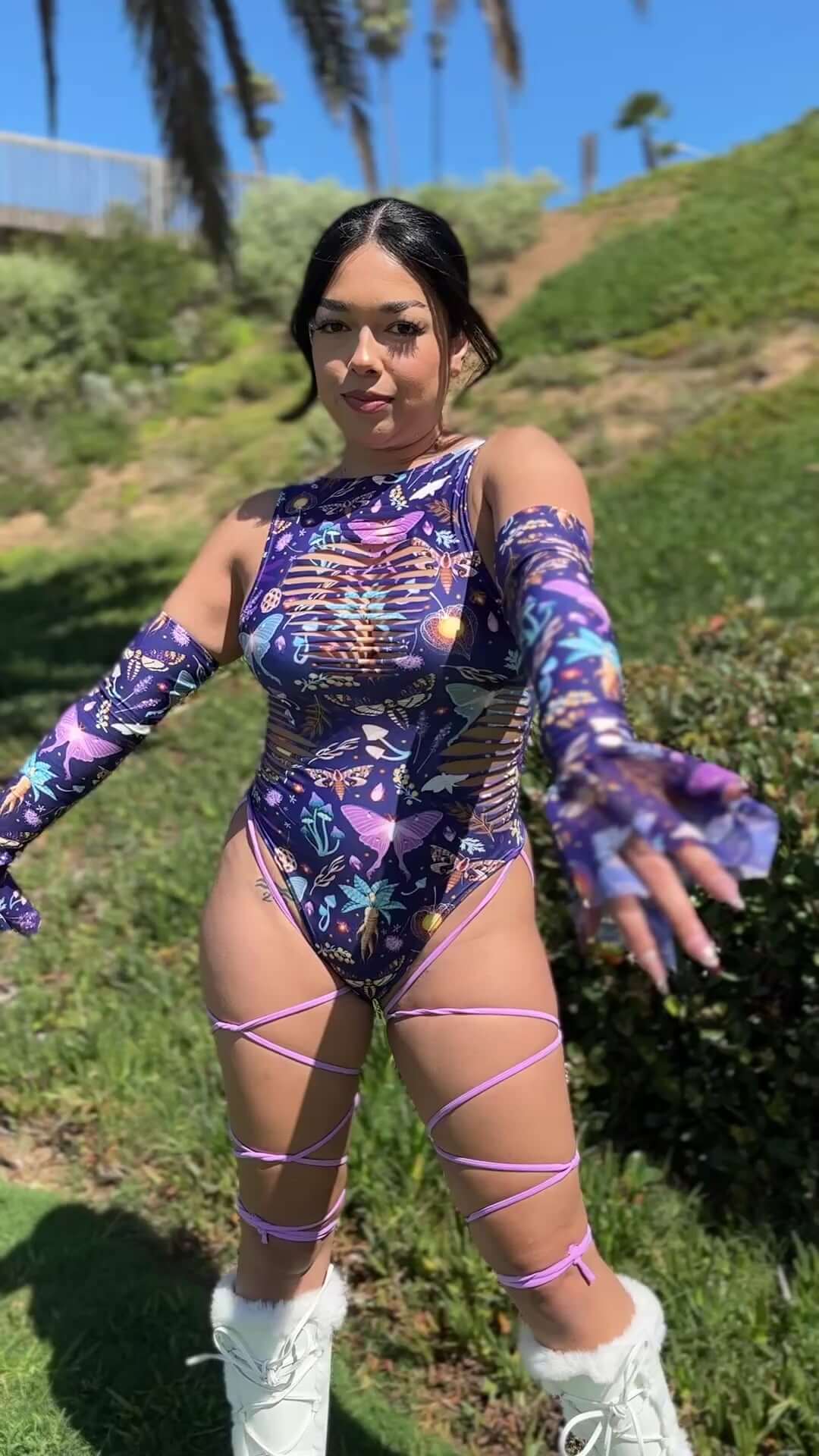 Model wearing Lucent Spellcaster Arm Sleeves with a colorful bodysuit in a sunny outdoor setting.