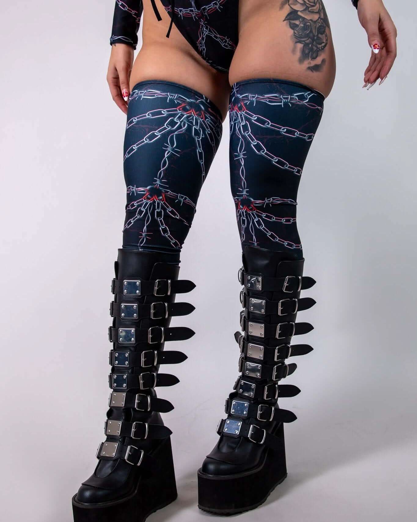 Purgatory Leg Sleeves with bold chain graphic, perfect for rave outfits and dancing, paired with stylish platform boots.