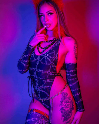 Model showcasing the Purgatory Temptation Cheeky One Piece, featuring chain graphics and bold styling against vibrant background.