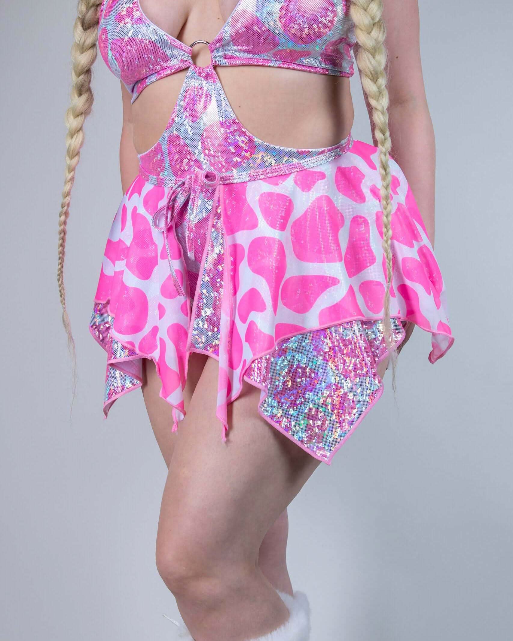 Model showcasing a pink sparkly cow print outfit, perfect for rave outfits, featuring a flared mini skirt.