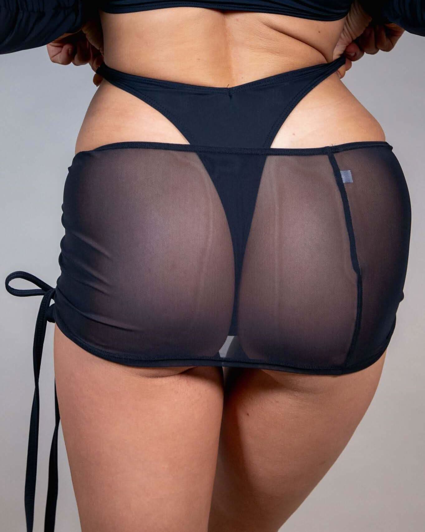 Black mesh cinch skirt showcasing adjustable tie drawcord and ruched effect, perfect for rave outfits and stylish layering.