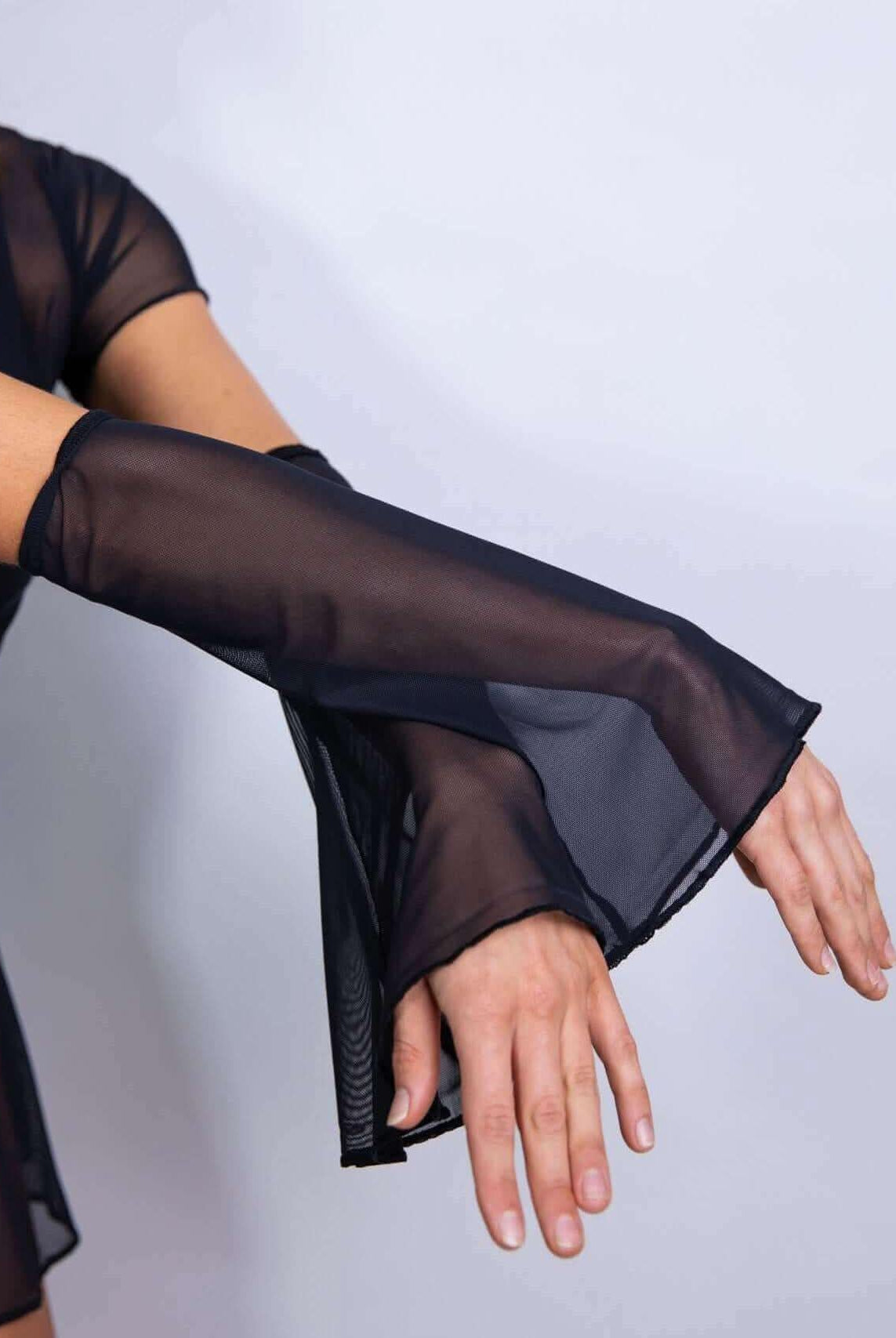 Black mesh flare sleeves worn on a model's arms, showcasing a flowy design perfect for rave outfits.