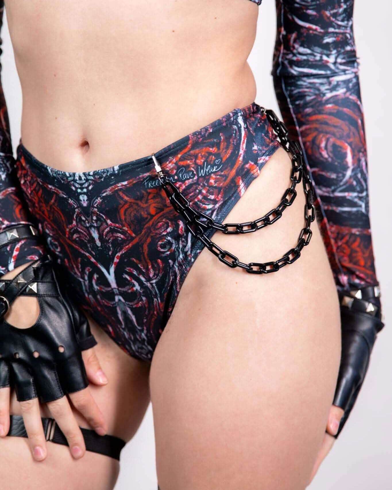 Model wearing a black and red patterned outfit with chain details, perfect for rave outfits, showcasing a bold festival look.