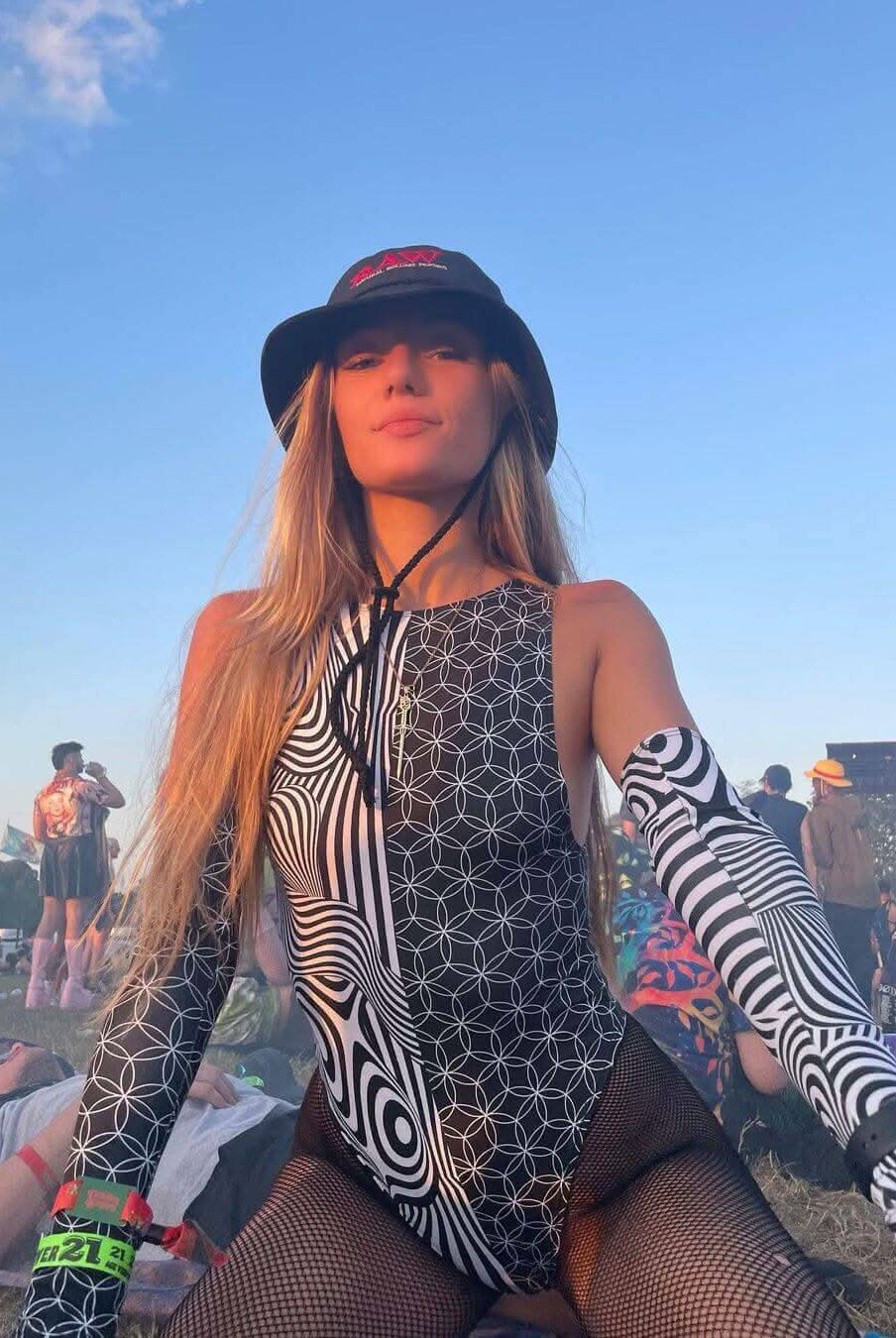 Model wearing Duality Sideboob Bodysuit at an EDM festival, showcasing bold black and white split print.