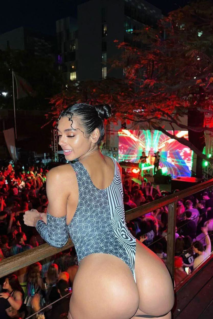 Woman wearing a black and white Duality Sideboob Bodysuit at an EDM festival, enjoying the vibrant crowd and atmosphere.