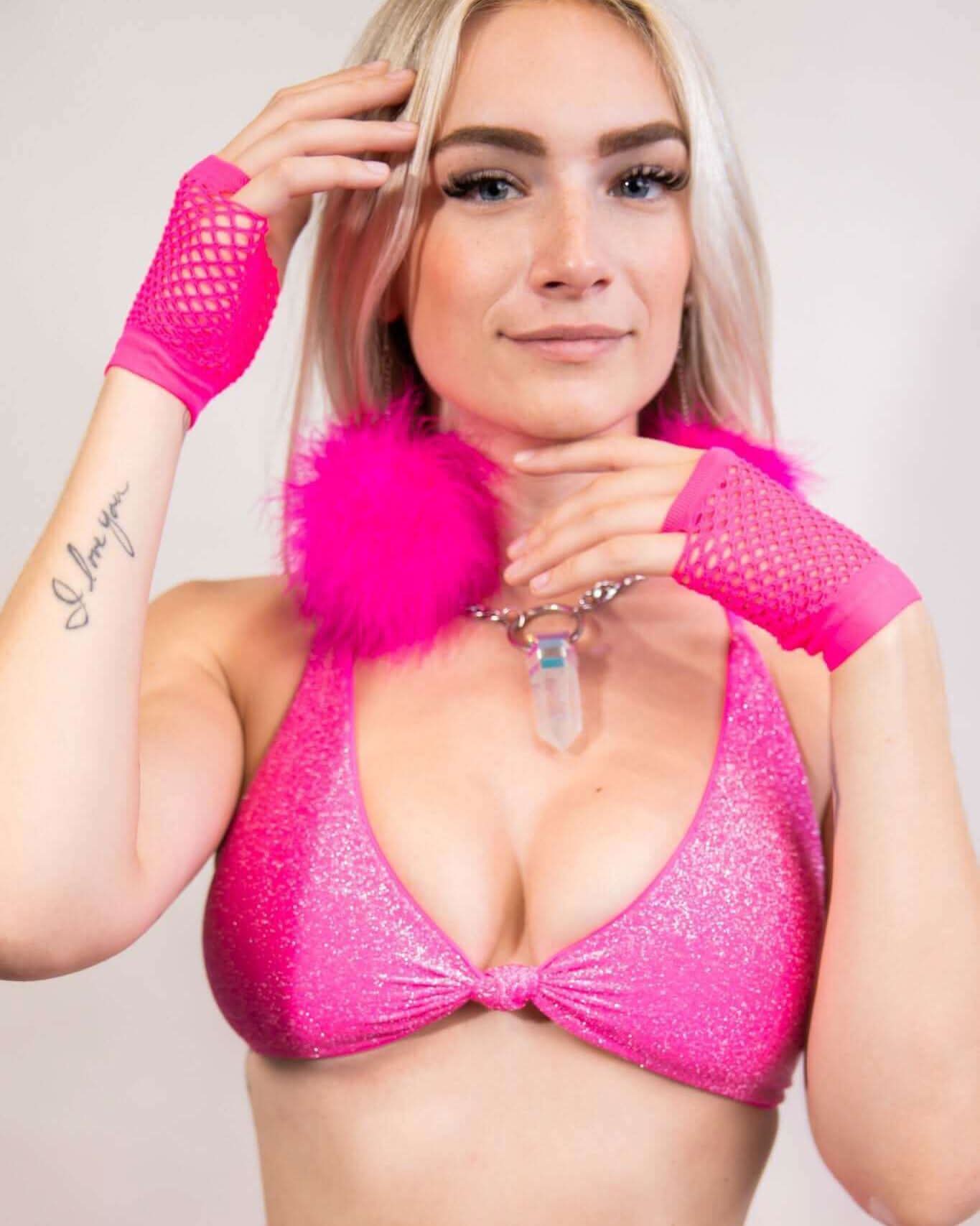 Model wearing neon pink fishnet gloves and a sparkly pink outfit, showcasing a bold festival look.