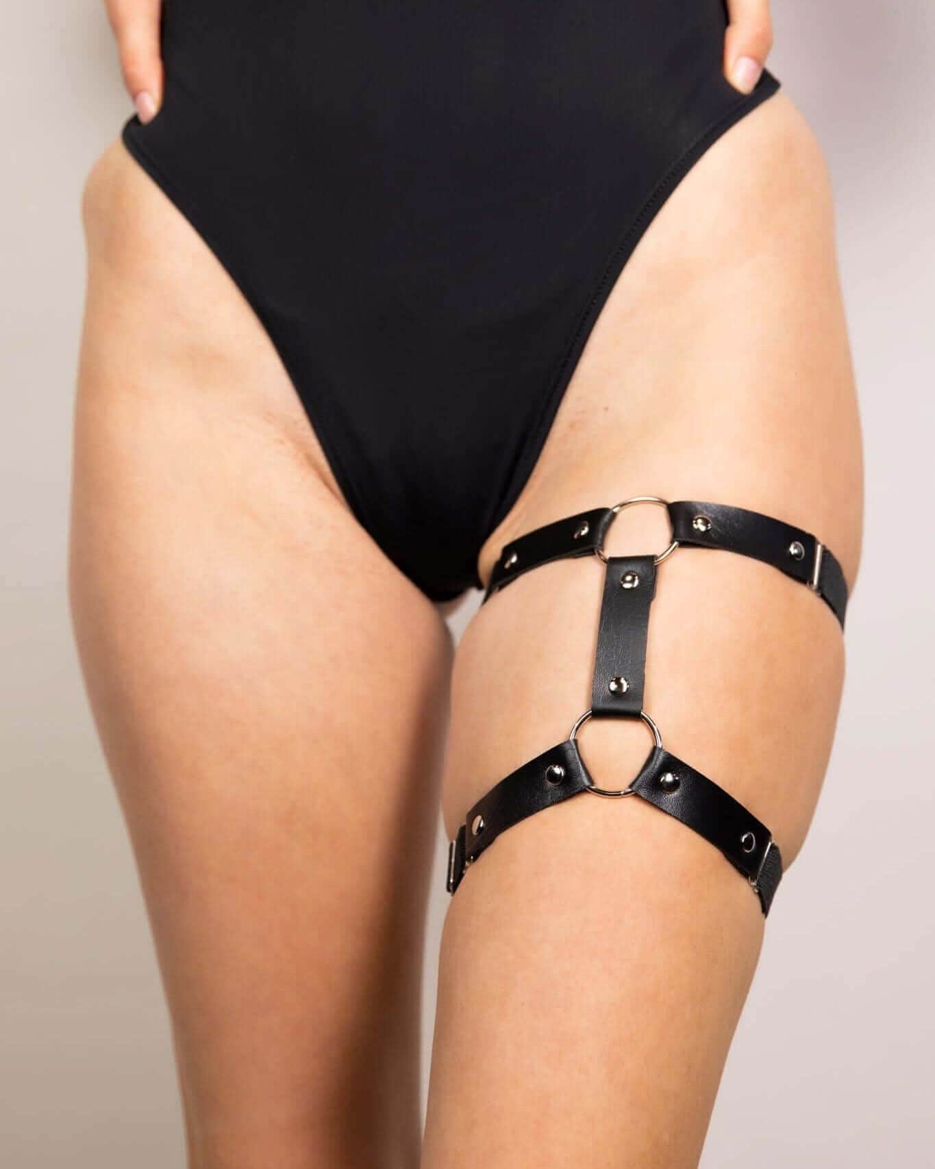 Black leather adjustable leg garter, perfect for edgy rave outfits and festival looks. High-quality elastic design.