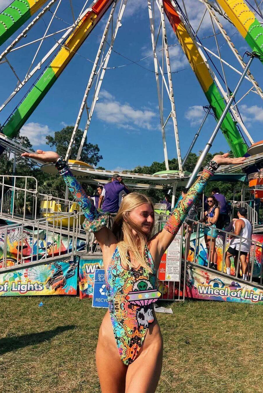 Woman in a psychedelic rainbow one-piece swimsuit celebrating at a vibrant carnival. Perfect for rave outfits and festivals.