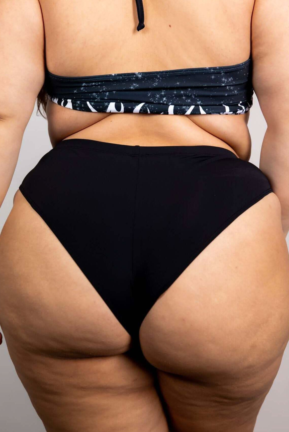 High-waisted matte black Brazilian bottoms showcasing a cheeky cut, perfect for rave outfits and summer fun.