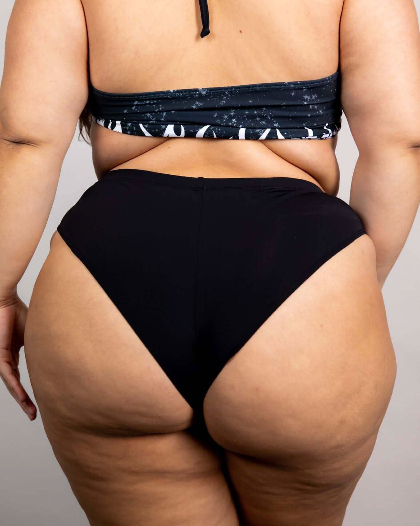 High-waisted matte black Brazilian bottoms showcasing a cheeky cut, perfect for rave outfits and summer fun.