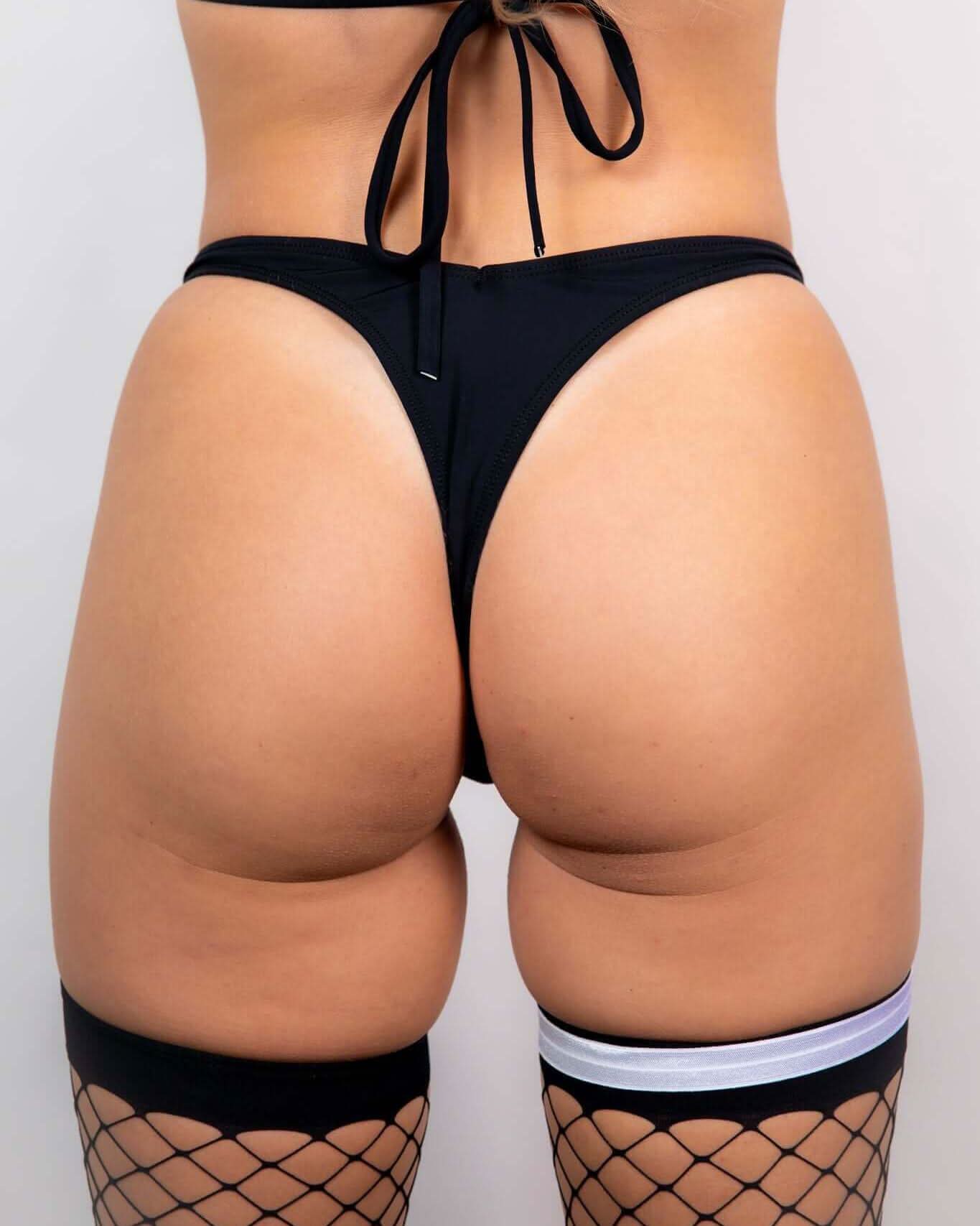 Matte Black Risk Bottoms featuring a Brazilian thong cut, paired with fishnet stockings for a daring rave outfit.