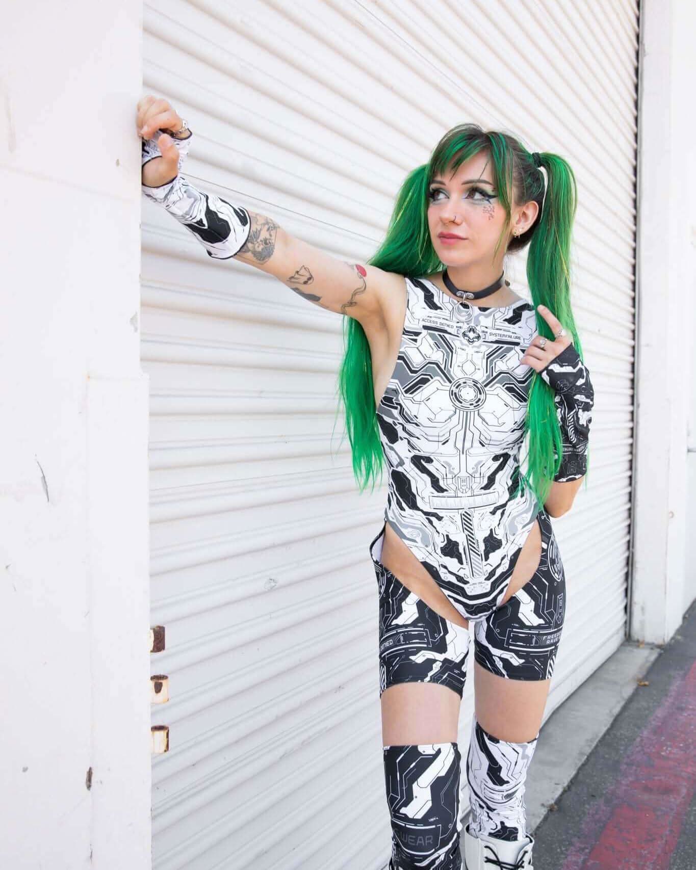 Model wearing Mechanoid Leg Sleeves, showcasing a futuristic rave outfit with colorful green hair.