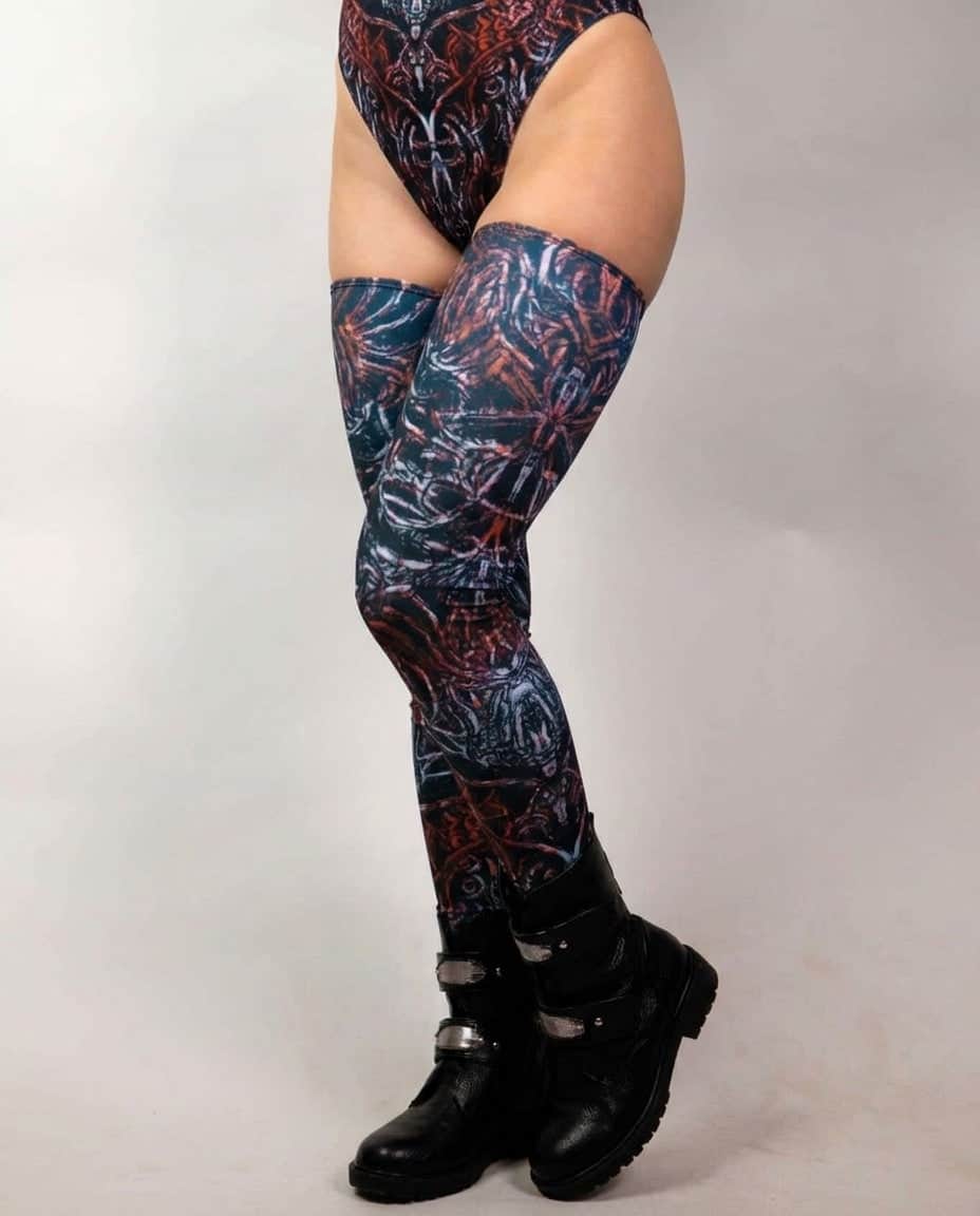 Darkness Leg Sleeves, three-quarter view showing dark abstract print from upper thighs to black buckled boots
