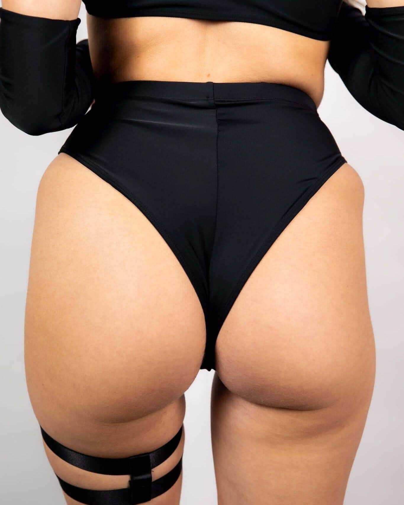 Matte black high waisted Brazilian rave pants shown from back view on model in festival outfit