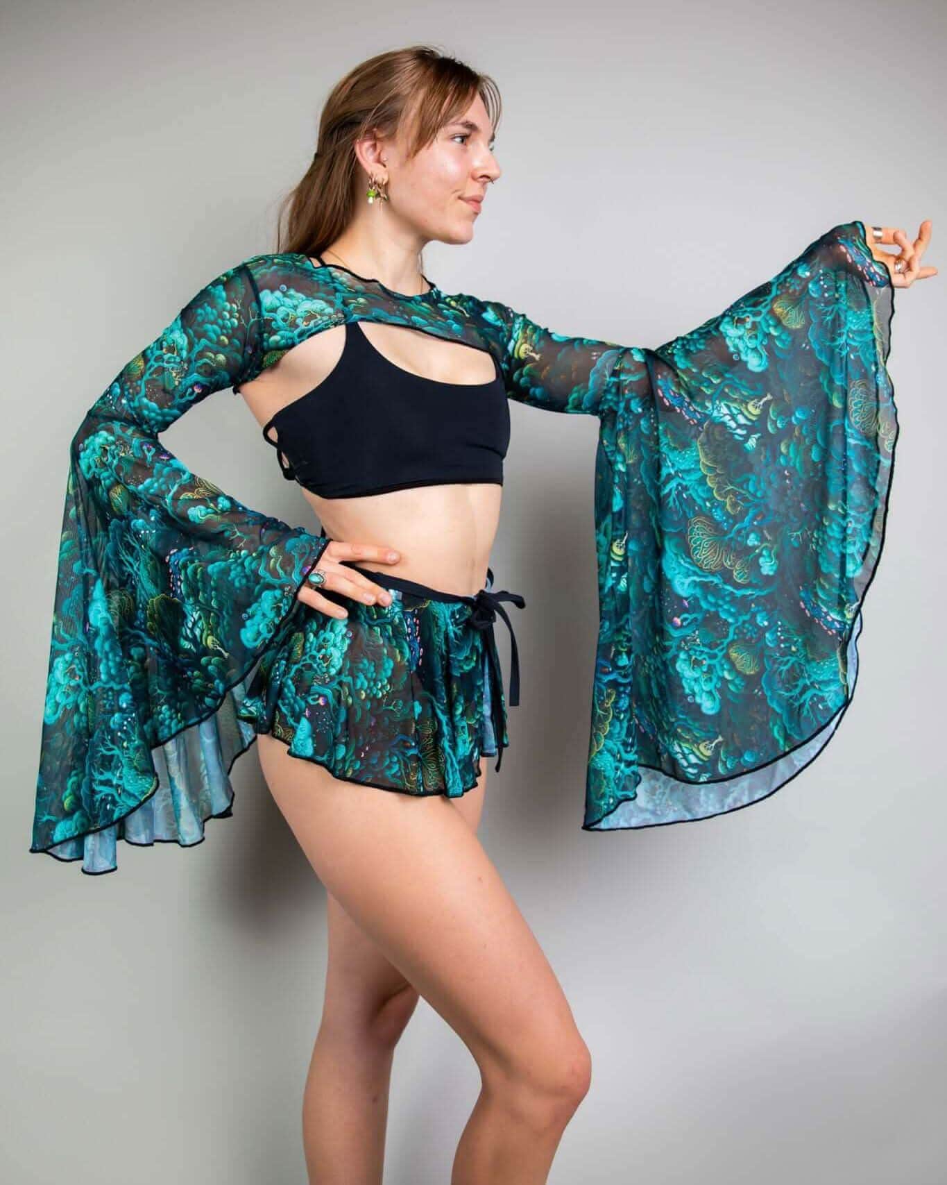Faewood mesh rave arm sleeves in teal and turquoise worn by model in side pose showing dramatic bell sleeves