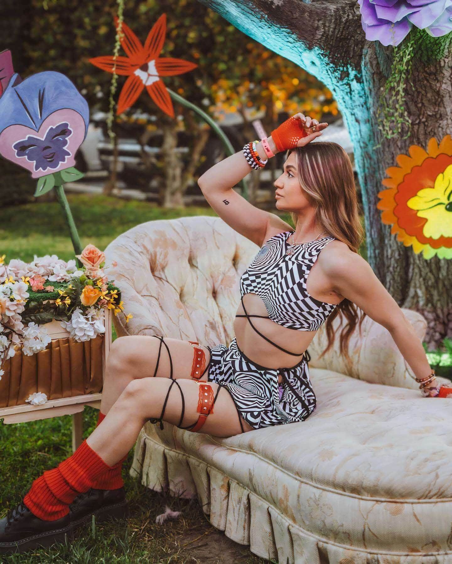 Woman wearing Distortion rave top with geometric print in outdoor lifestyle setting with decorative flower overlays