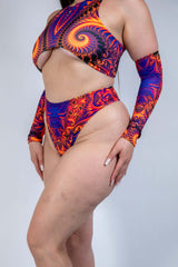 Model wearing a colorful psychedelic rave outfit featuring a crop top and high-waisted bottoms.