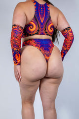 Model wearing a vibrant orange and purple rave outfit, featuring a crop top and high-waisted bottoms, ideal for festivals.