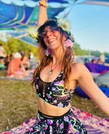 enthusiastic raver in a black and purple mushroom patterned outfit with matching accessories in the middle of a festival crowd