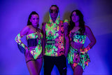 Three models showcase vibrant glow-in-the-dark rave clothing in neon patterns, perfect for festival season.