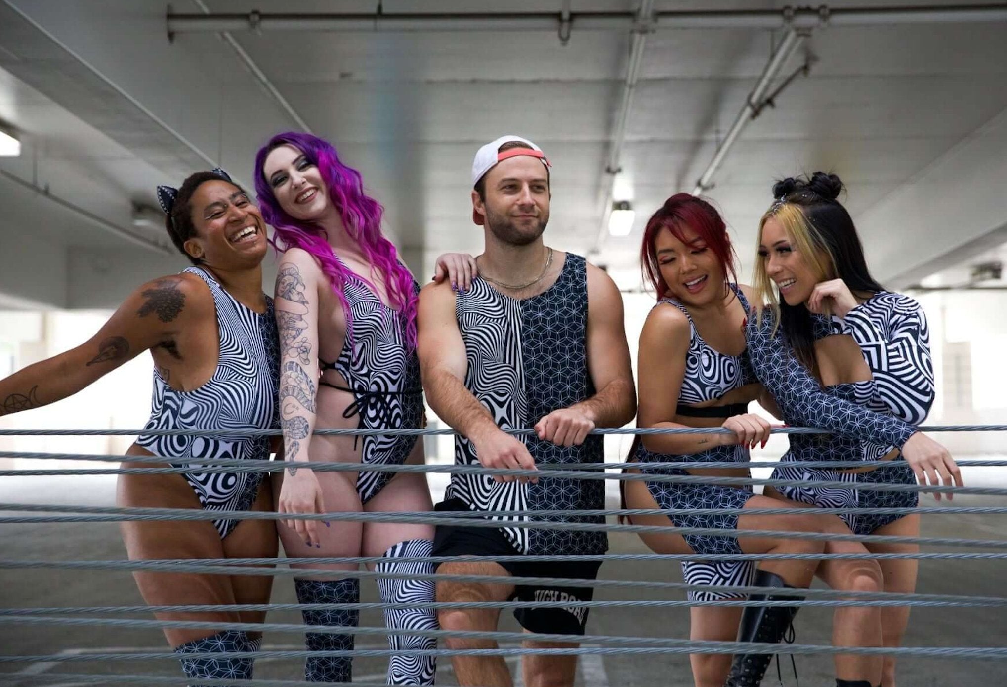 Group of friends in matching black and white geometric rave outfits pose together, showcasing trendy festival fashion and camaraderie