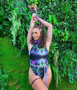 rave girl wears neon festival outfit against a lush green backdrop