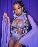 Poc rave girl poses with a mystical aura in a sparkling lilac rave set, complemented by lavender backdrop