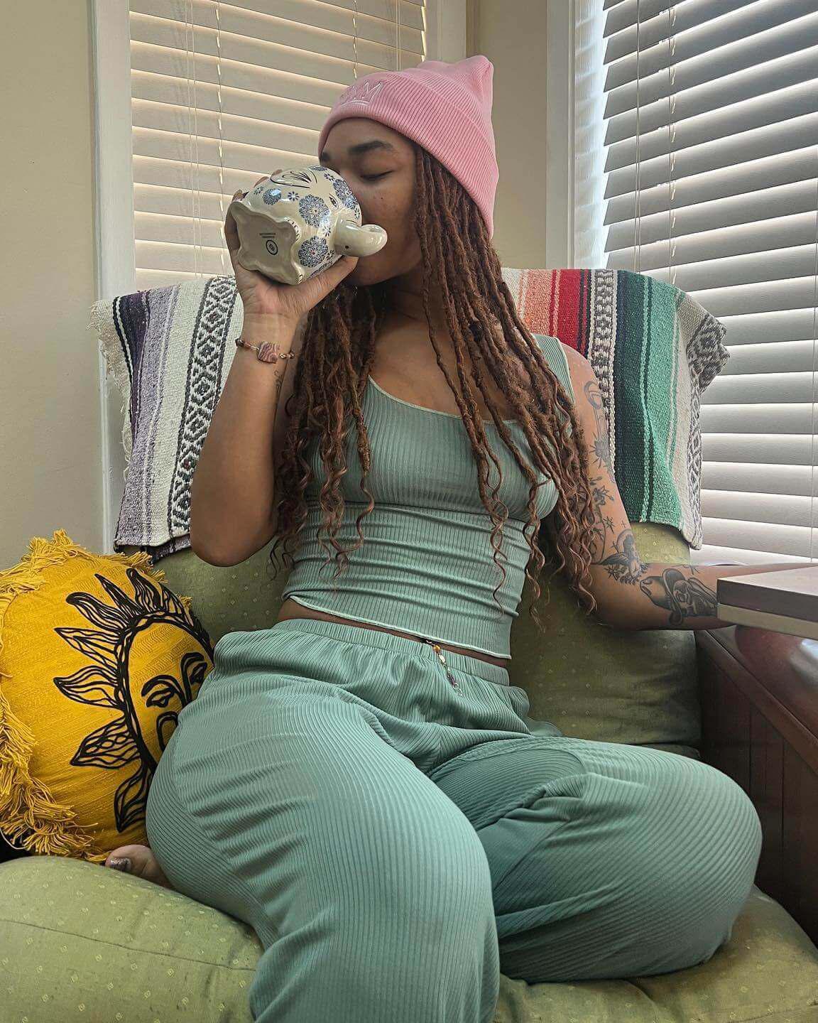 Woman in sea spray ribbed lounge tank sipping tea on a cozy chair, showcasing comfortable casual style perfect for relaxing.