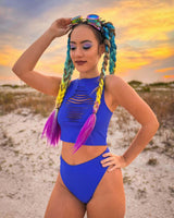 Vibrant blue Freedom Rave Wear outfit paired with colorful braided hair, posed against a sunset backdrop, enhancing the festival vibe.
