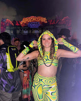 raver wears colorful yellow and green festival outfit admist the crowd of a music festival exuding happiness