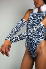 An up-close photo of the side of a girl wearing black and white tribal printed arm sleeves and a matching bodysuit.
