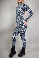 A blonde girl wearing a black and white tribal printed catsuit, with long sleeves and long pants.