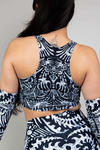 A photo of a girl wearing a black and white tribal printed crop top with matching shorts and arm sleeves looking away from the camera.