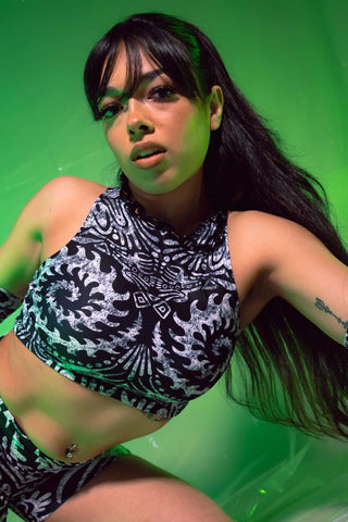 A photo of a girl wearing a black and white tribal printed crop top in front of a green background.