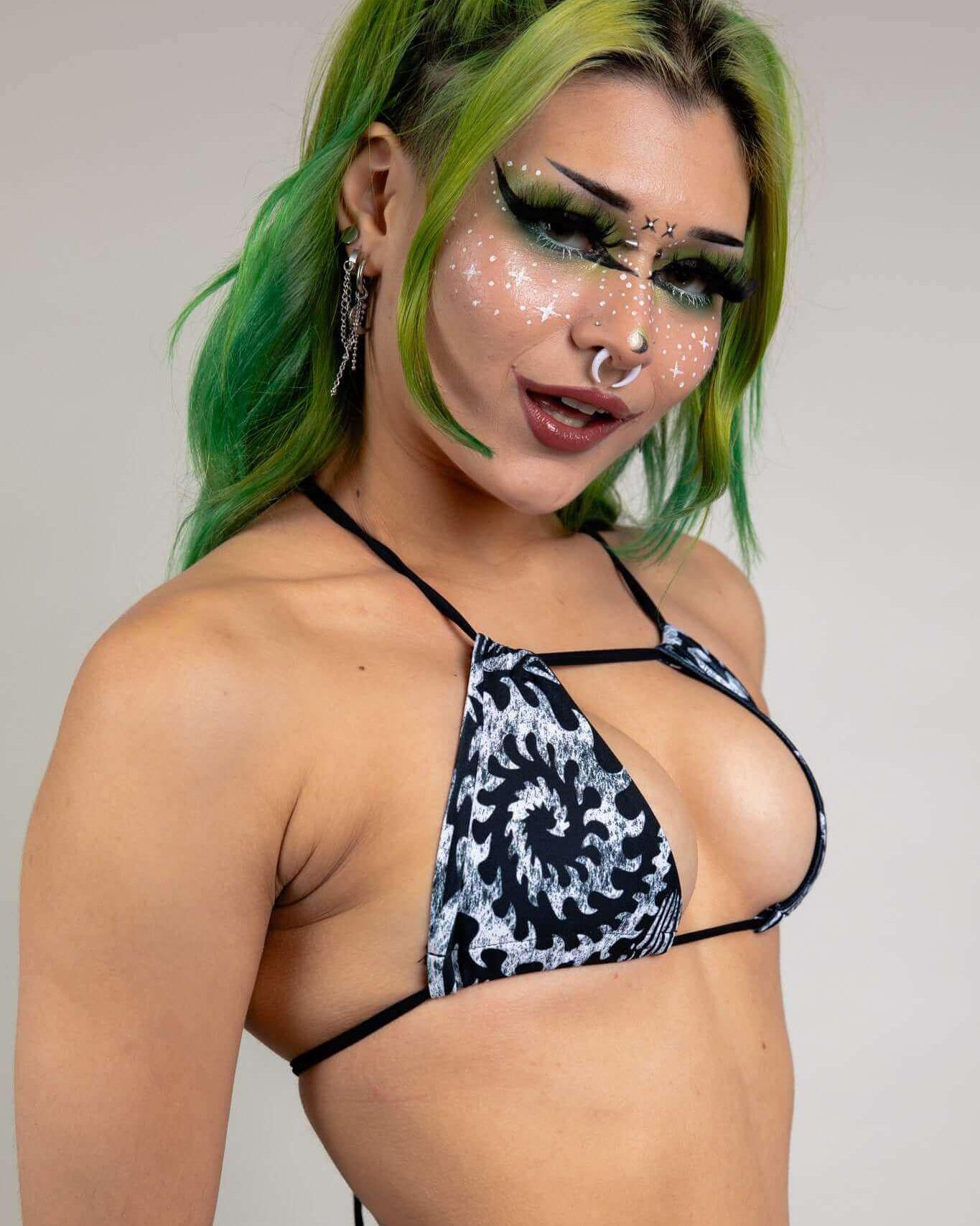 Model showcasing the Archaic Strappy Bikini Top with unique design, ideal for rave outfits, featuring vibrant green hair and bold makeup.