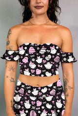 Model in a black off-shoulder bardot top with pink and white spooky ghost print, paired with matching skirt.