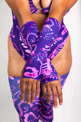 Model wearing Freedom Rave Wear bodysuit with purple dinosaur print and matching gloves, ideal for rave outfits.