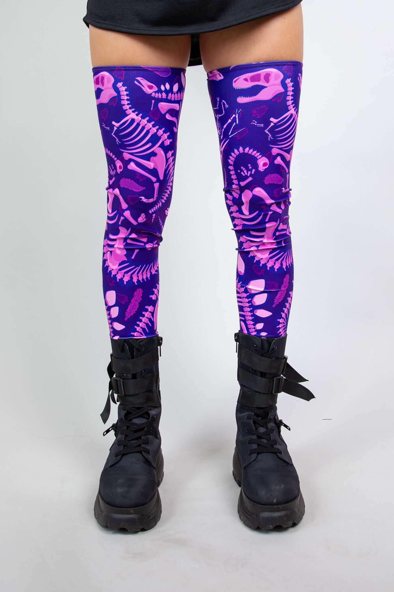 Model wearing Freedom Rave Wear thigh-high leg sleeves with purple dinosaur print and black boots, perfect for rave outfits.