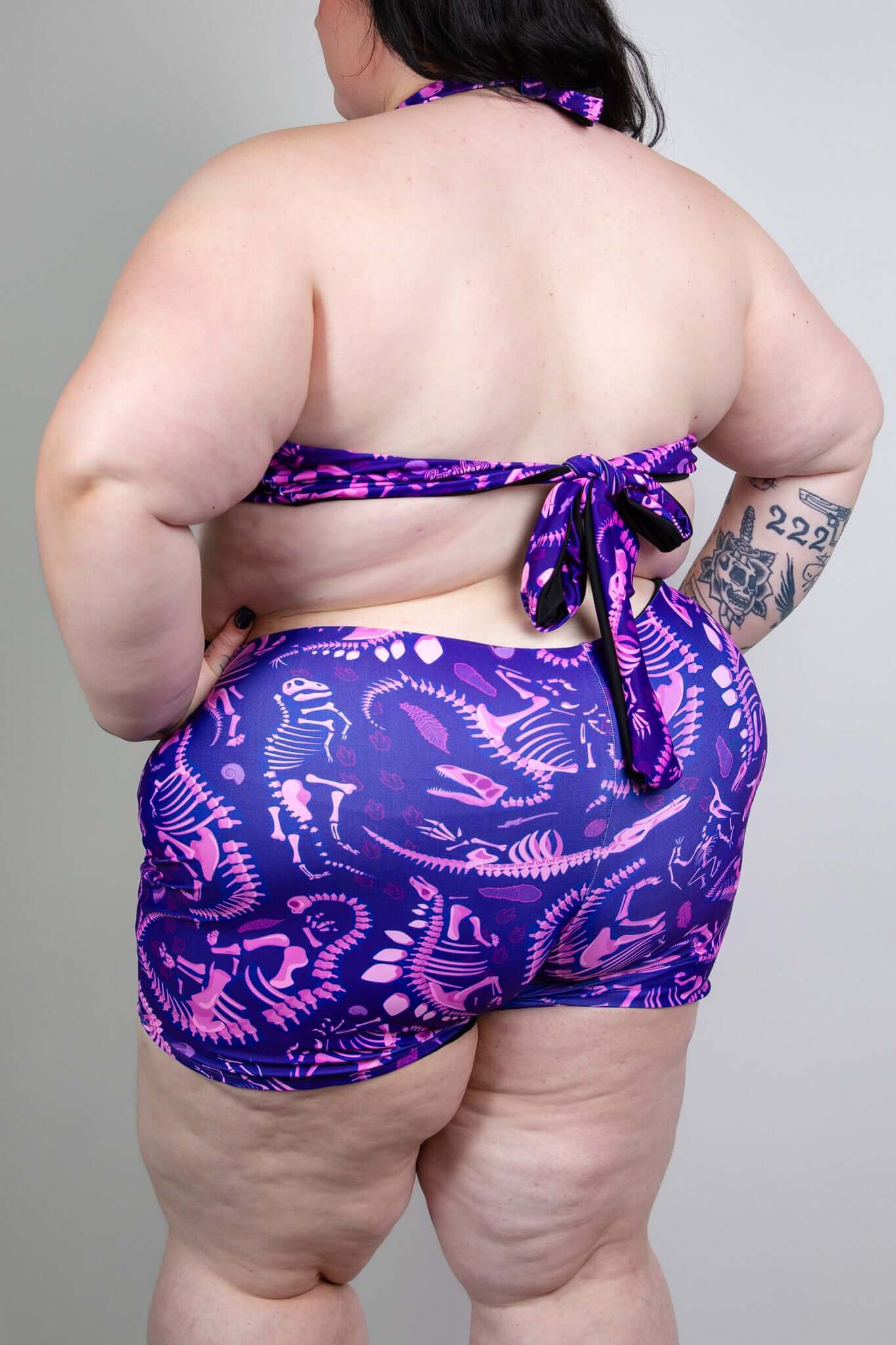 Model wearing Freedom Rave Wear romper with a purple dinosaur print, shown from the back, perfect for stylish rave outfits.