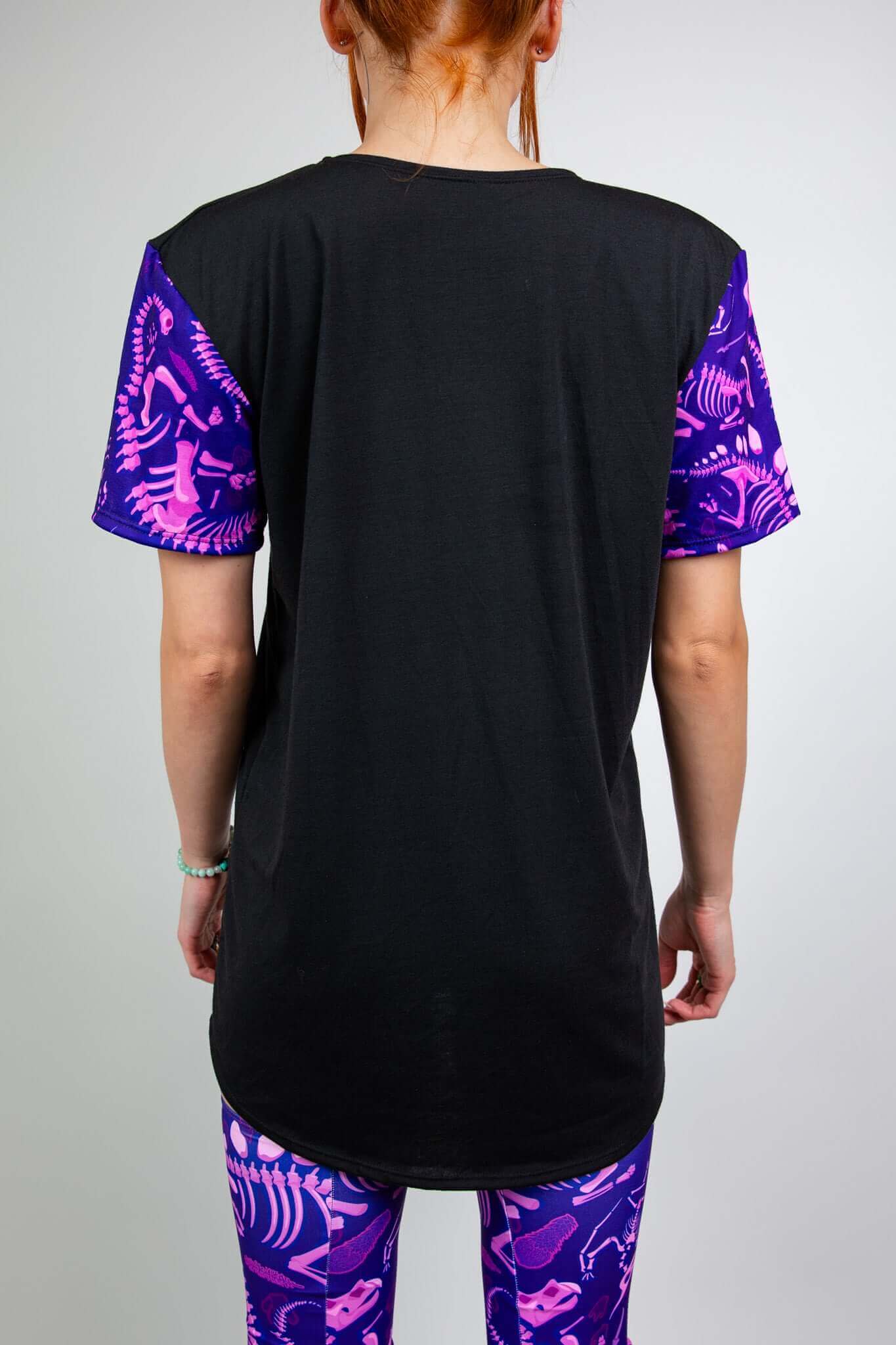 Model wearing Freedom Rave Wear black t-shirt with purple dinosaur print sleeves and matching leg sleeves, shown from the back.