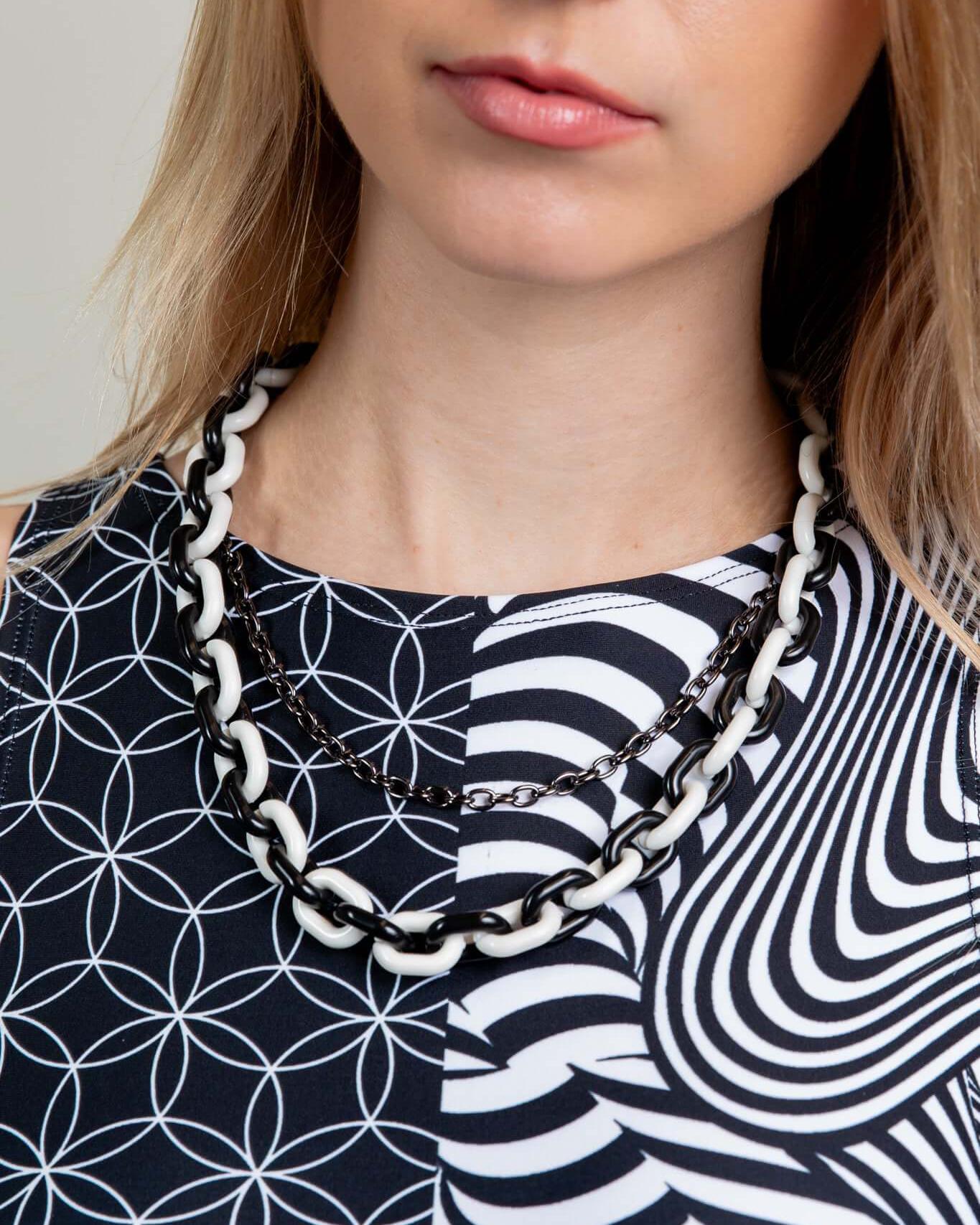 Close-up of a woman wearing a black and white balance chain, ideal for rave outfits, showcasing contrasting colors and design.