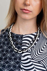 Close-up of a woman wearing a black and white balance chain, ideal for rave outfits, showcasing contrasting colors and design.