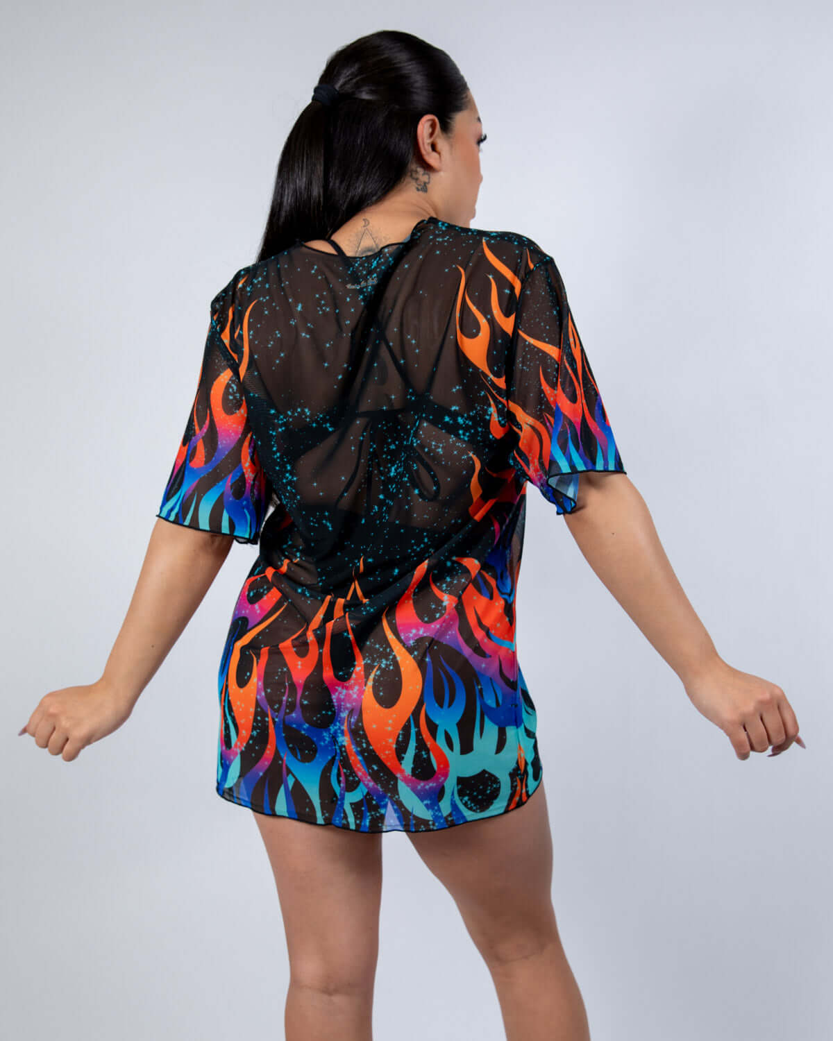 Back view of a woman in a Blaze Mesh Oversized Tee with bold flame print, perfect for rave outfits.