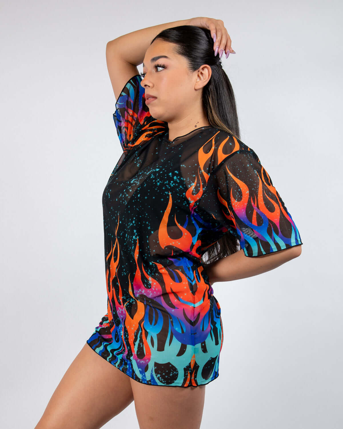 Woman wearing the Blaze Mesh Oversized Tee with colorful flame print, perfect for rave outfits and night events.