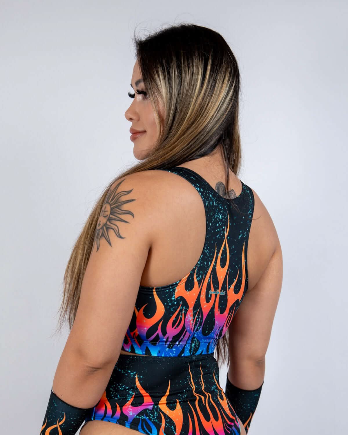 Back view of woman wearing Blaze flame pattern rave top with colorful fire design and mesh details
