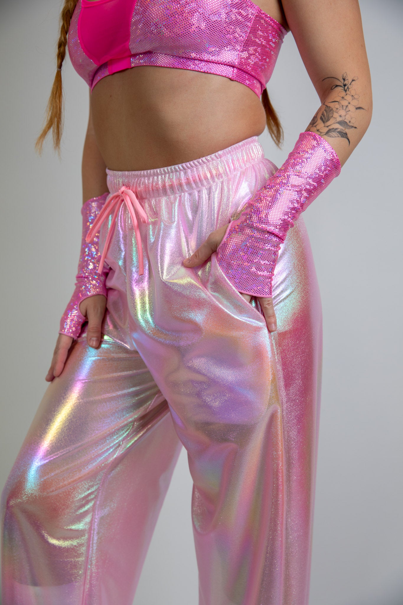 Bubble Gum Lucy Pants in iridescent pink, angled front view, high-waisted with shimmer fabric, ideal for rave fashion and festival style.