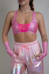 Model wearing a Bubble Gum Holo V Free Top, front view showcasing a shiny pink holographic fabric with a deep V neckline, perfect for rave and festival outfits.